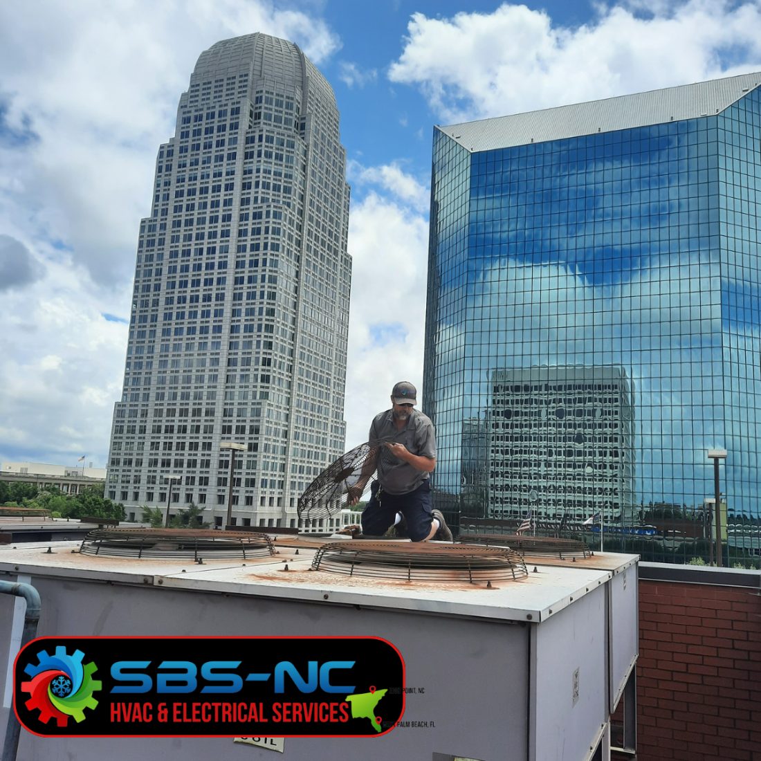 An SBS-NC technician replacing a condenser fan guard on a rooftop unit in downtown Winston-Salem, NC