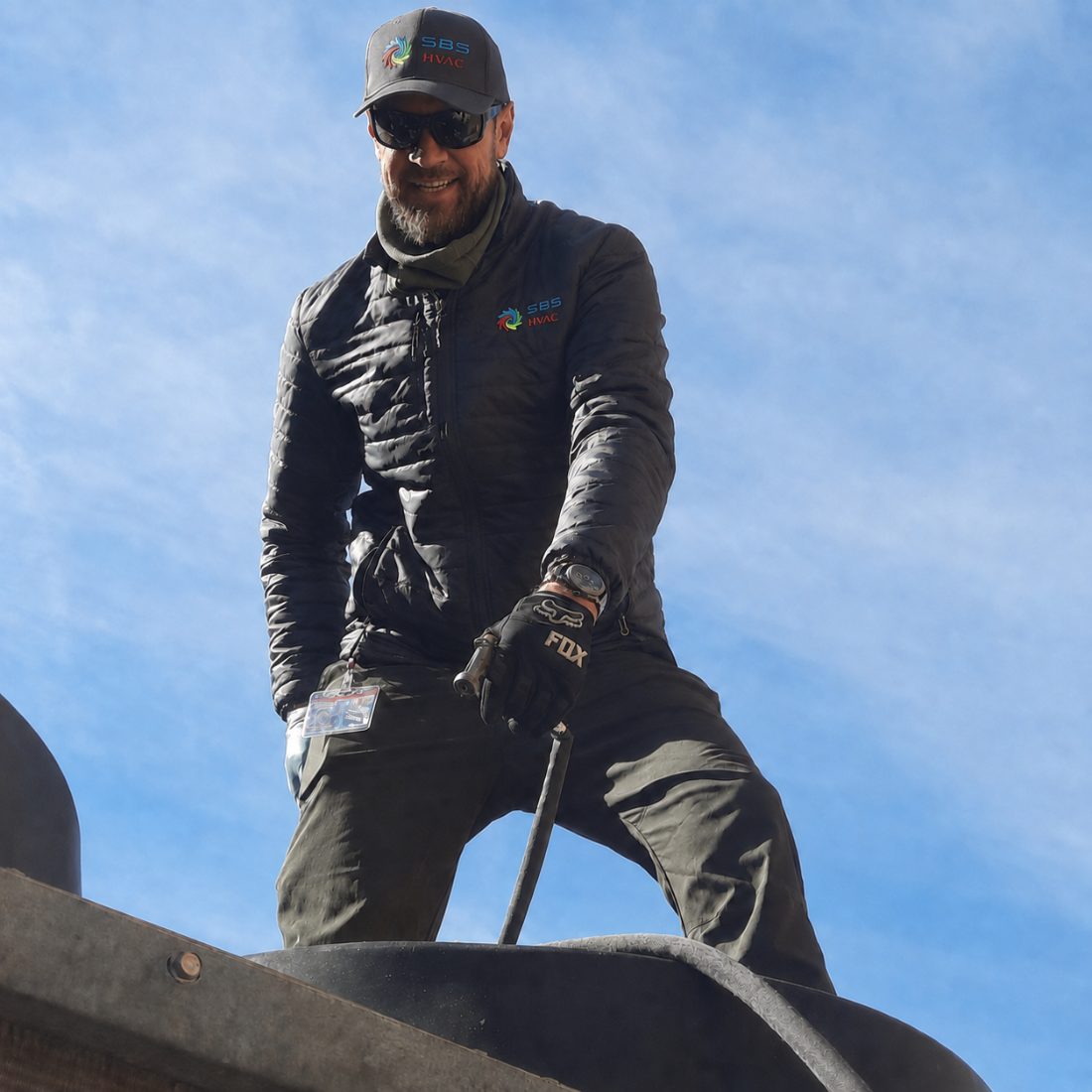 An SBS-NC technician in branded gear servicing a rooftop unit
